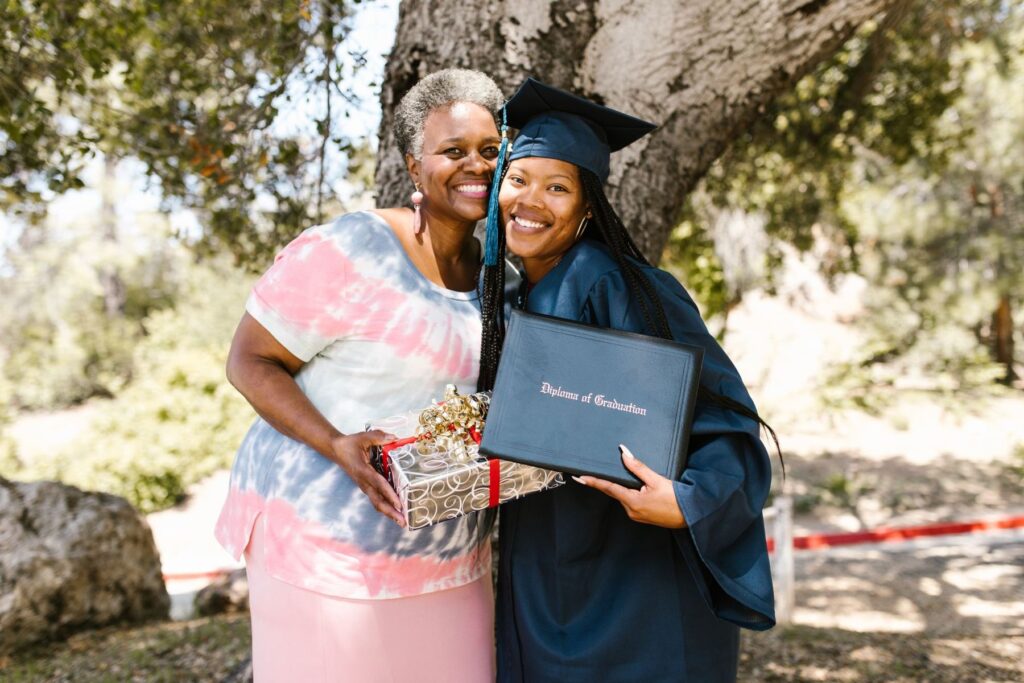 A graduate in cap and gown hugging her mother