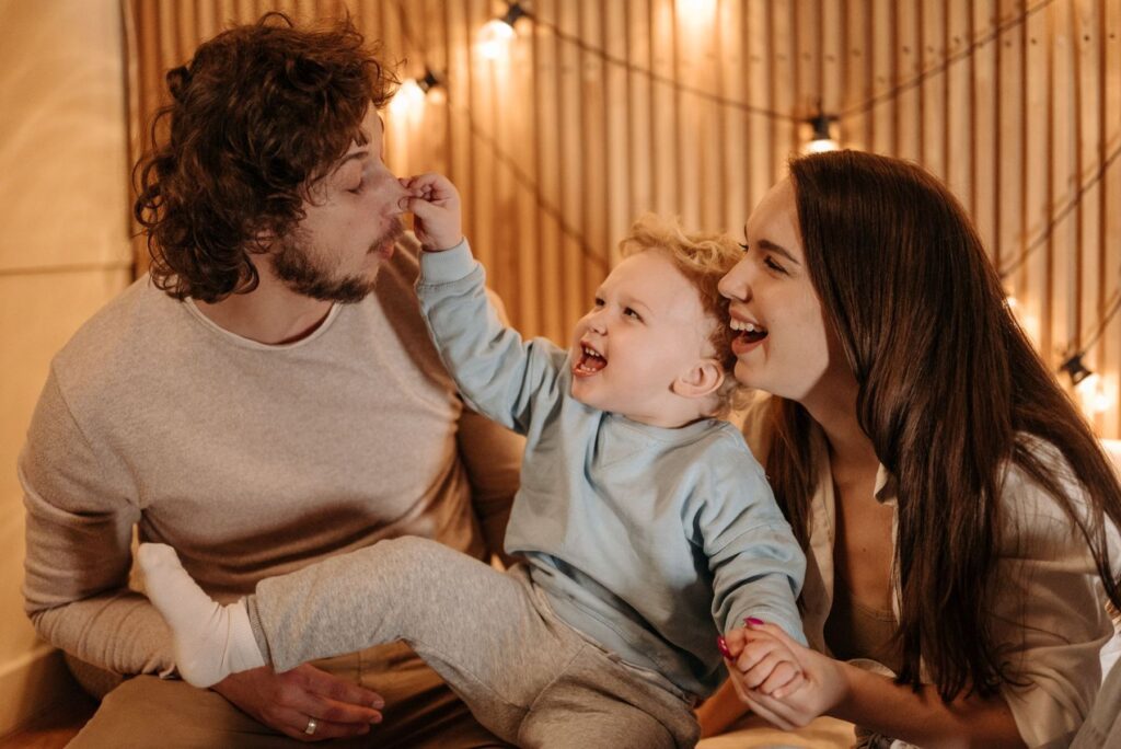A father, mother and toddler laughing together at home