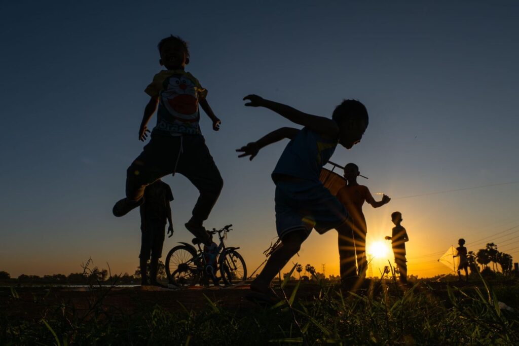 Children running and jumping outdoors at sunset