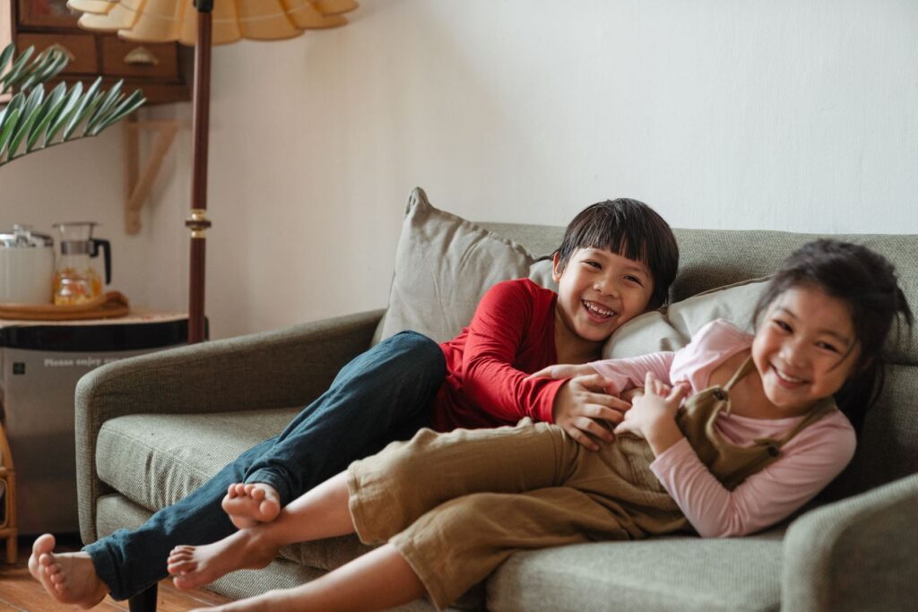 Two children laughing together on a couch
